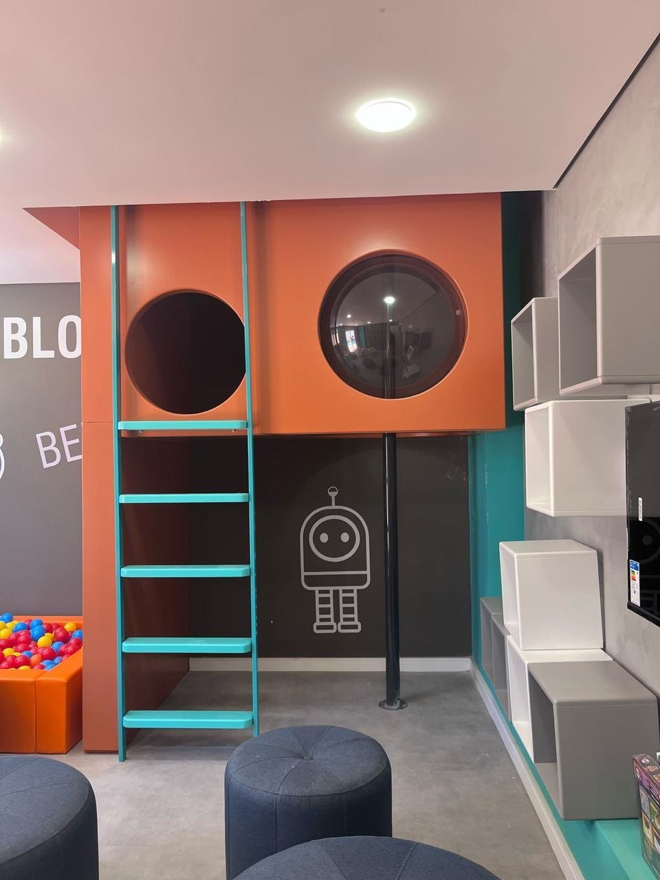 Brinquedoteca com móvel laranja de janelas redondas e escada